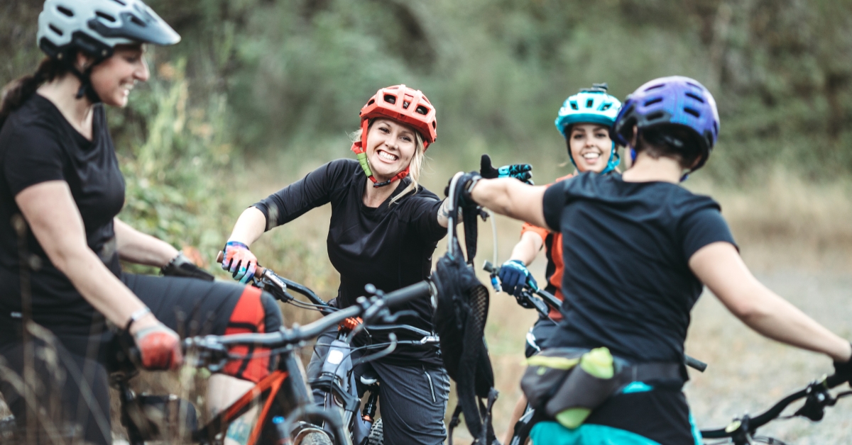 Teens biking and high-fiving on a trail, showcasing implementing a wellness program for your teens.