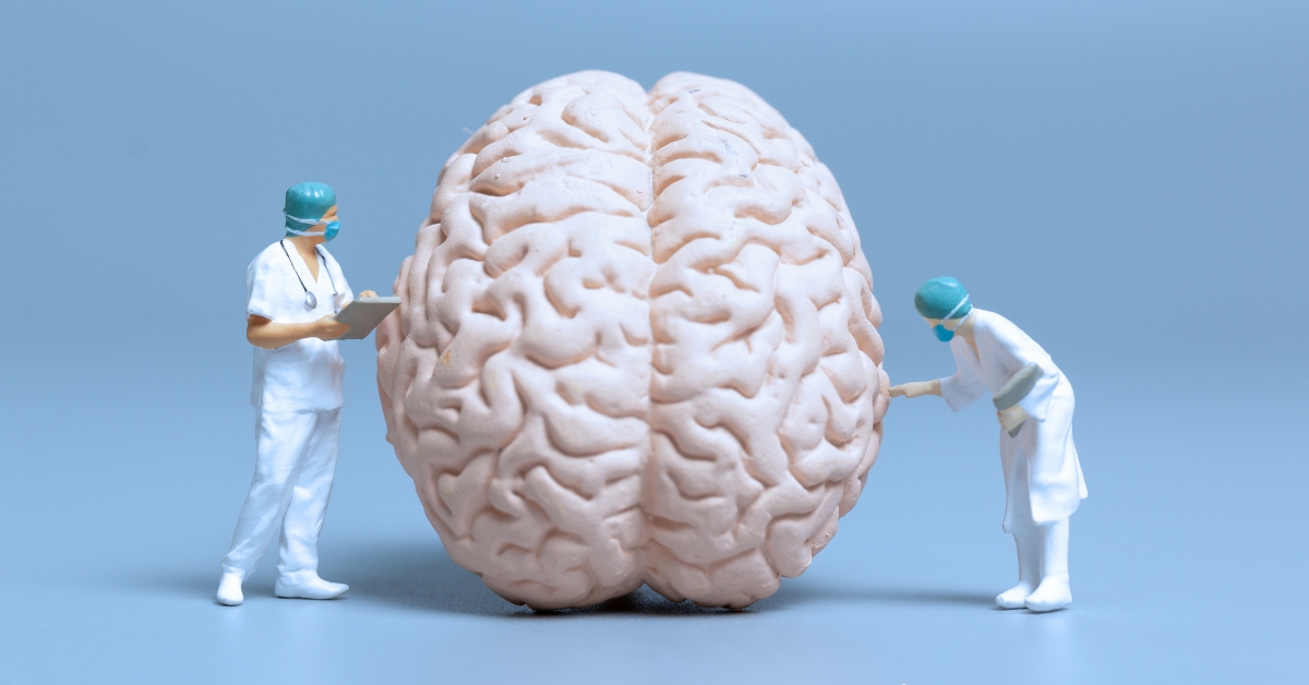 Two miniature doctors examine a large brain model, illustrating ways to rewire the brain from addiction.