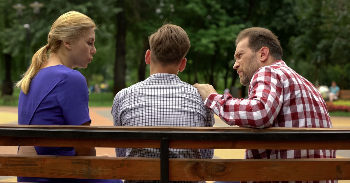 A couple talking to a young man on a park bench, illustrating how trauma therapy can help with anxiety and depression.