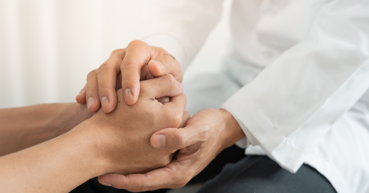 A doctor holding a patient's hand, suggesting someone may need mental health treatment naturally.