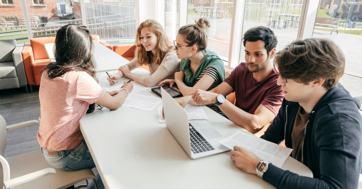 A group of students discussing and researching on laptops, illustrating how to choose the right online anxiety treatment program.