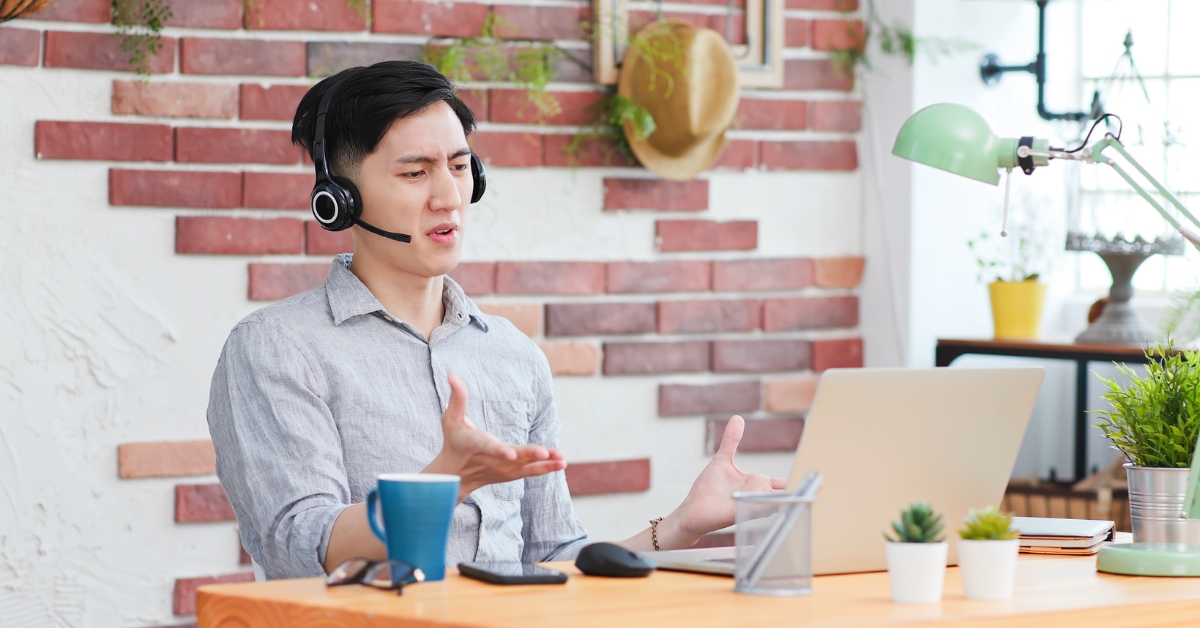 A man wearing headphones, engaging in an Anxiety Treatment Online session, gesturing while talking to his laptop.