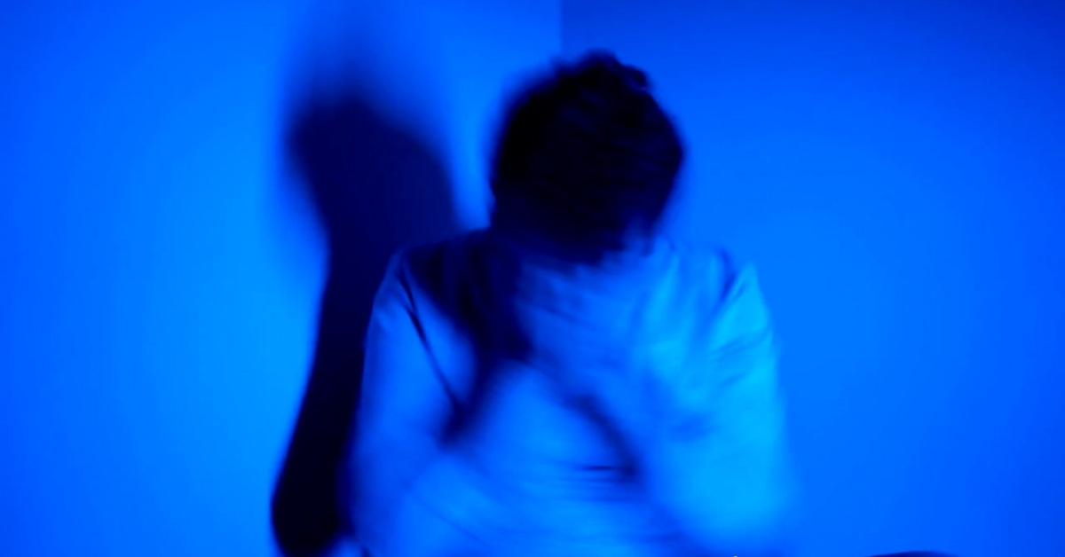 A person holds their head in distress under blue light, illustrating: What are Some Effective Treatment Options Available for Mental Health Issues?