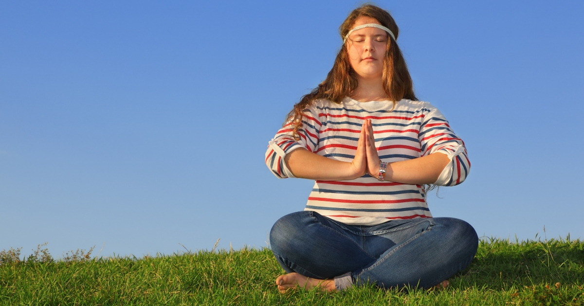 A teen girl meditating outdoors, illustrating meditation practices for depression relief for teens.