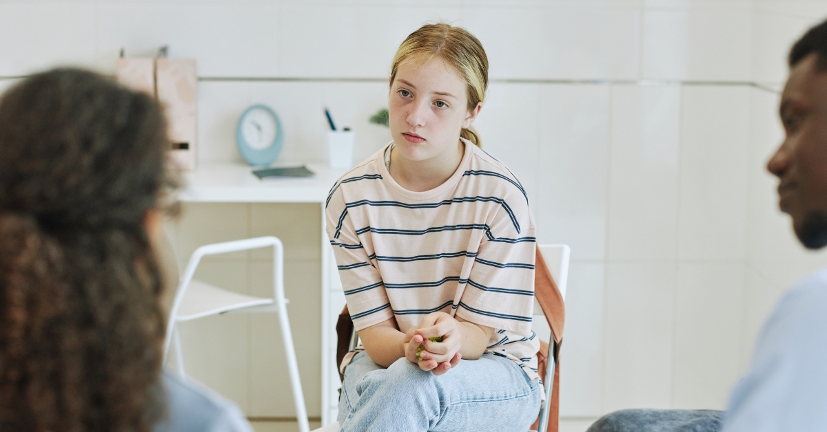 A teenage girl in a striped shirt during a counseling session, illustrating youth therapy services.