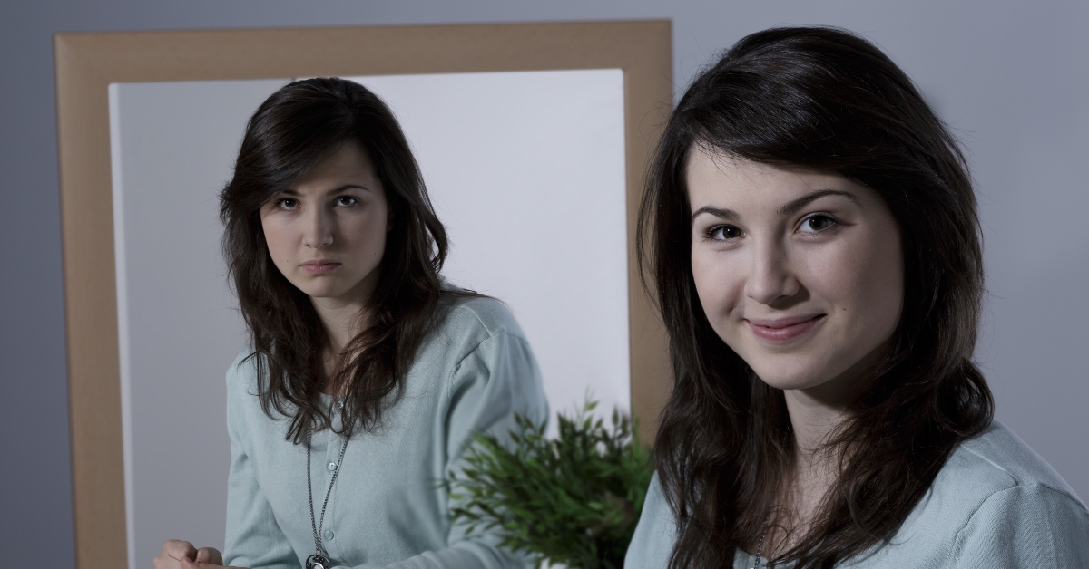 A woman shows a serious and smiling face in a mirror, illustrating: Help Someone with Bipolar Disorder Who Refuses Help?