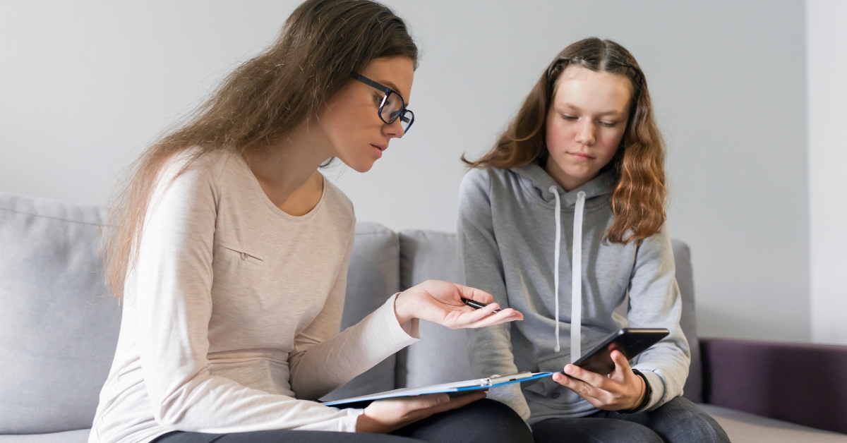 A counselor and a teenager discussing on a couch, illustrating different approaches in youth counseling.