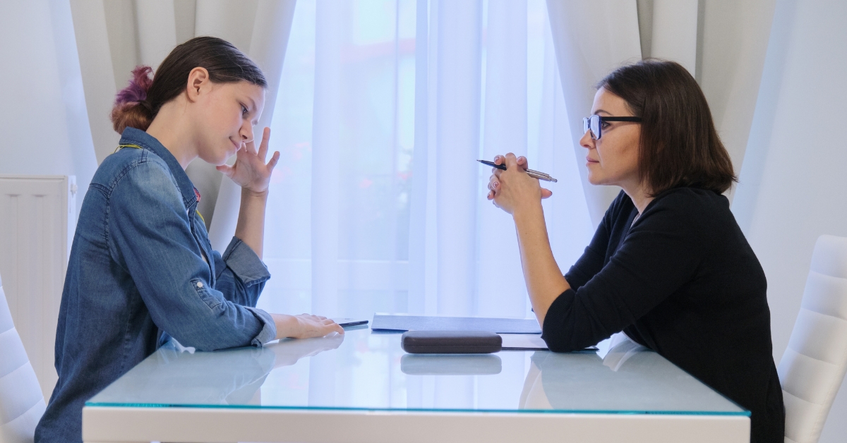 A young woman in a denim jacket in a serious discussion with a therapist during an Intensive Outpatient Program Mental Health session.