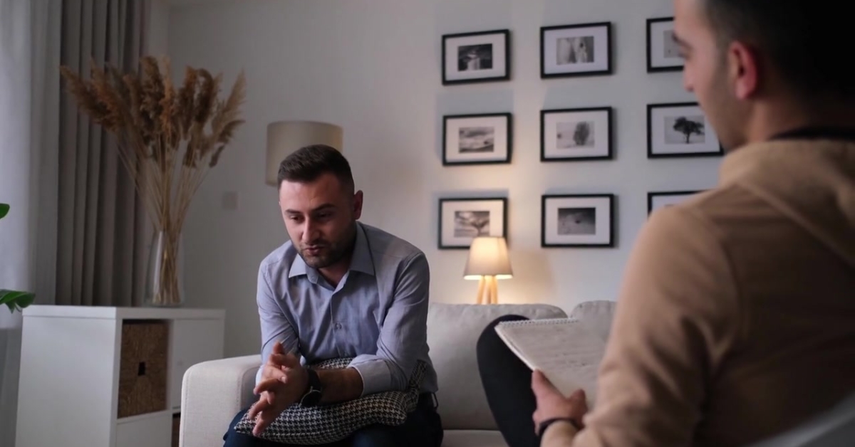 A man in a therapy session, seated on a couch, discussing concerns, symbolizing a teen needing occupational therapy.