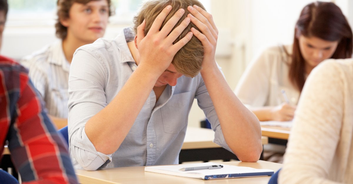 Student holding head in frustration during class, illustrating academic struggles related to anxiety disorders.