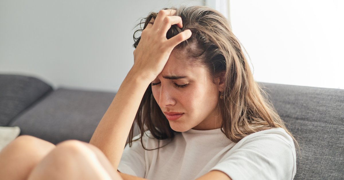 Woman holding her head in distress, representing the relationship between anxiety and depression.