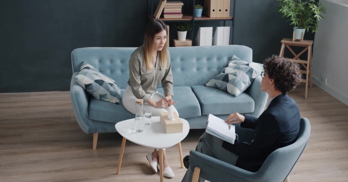 A woman in a therapy session, sitting on a couch, addressing anxiety and depression through mood therapy.