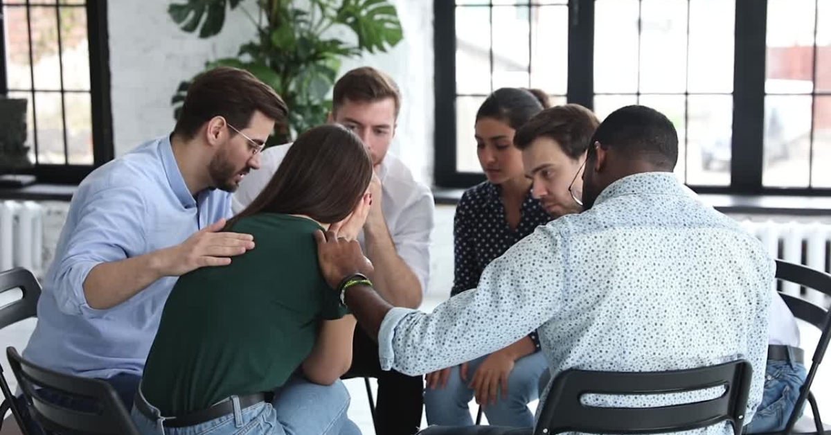 A group of individuals offering comfort and support to a distressed peer, illustrating peer support in social anxiety programs.