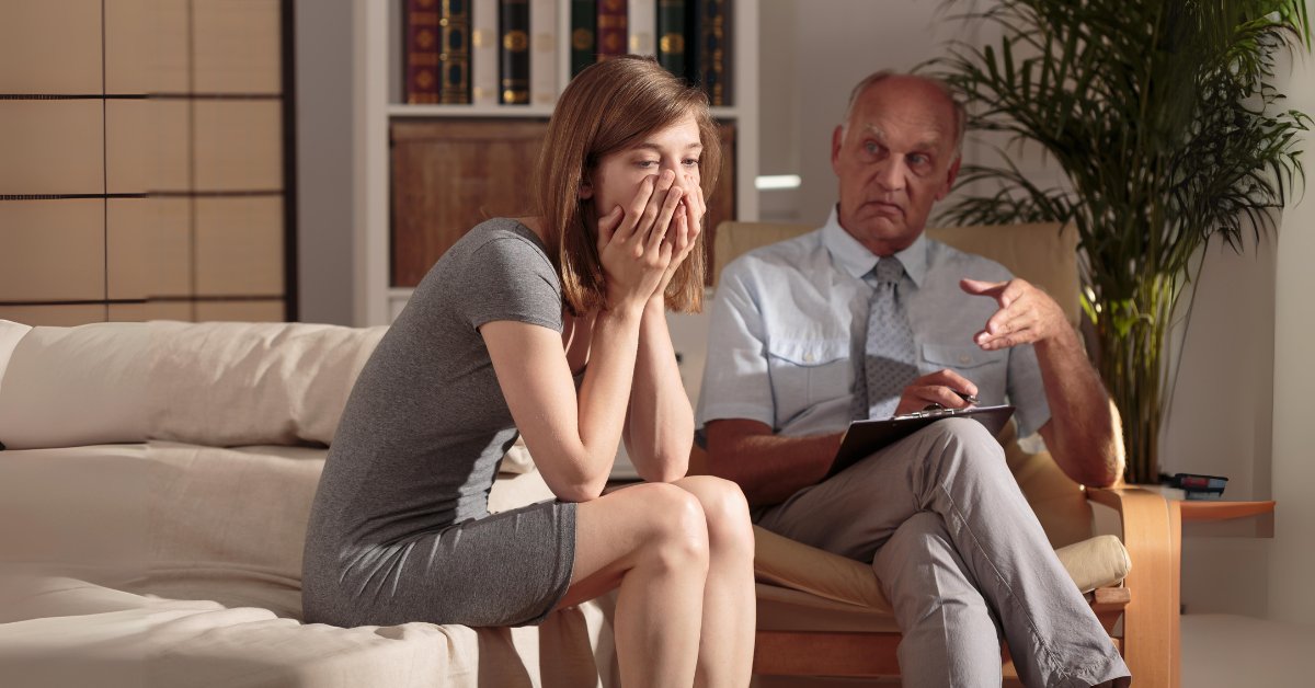 Woman showing distress in a therapy session, illustrating trauma-induced anxiety during counseling.