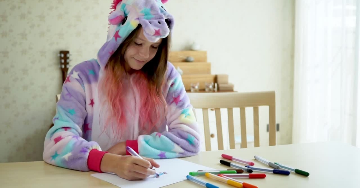 A girl in a unicorn onesie drawing with markers, illustrating art therapy techniques for depression.