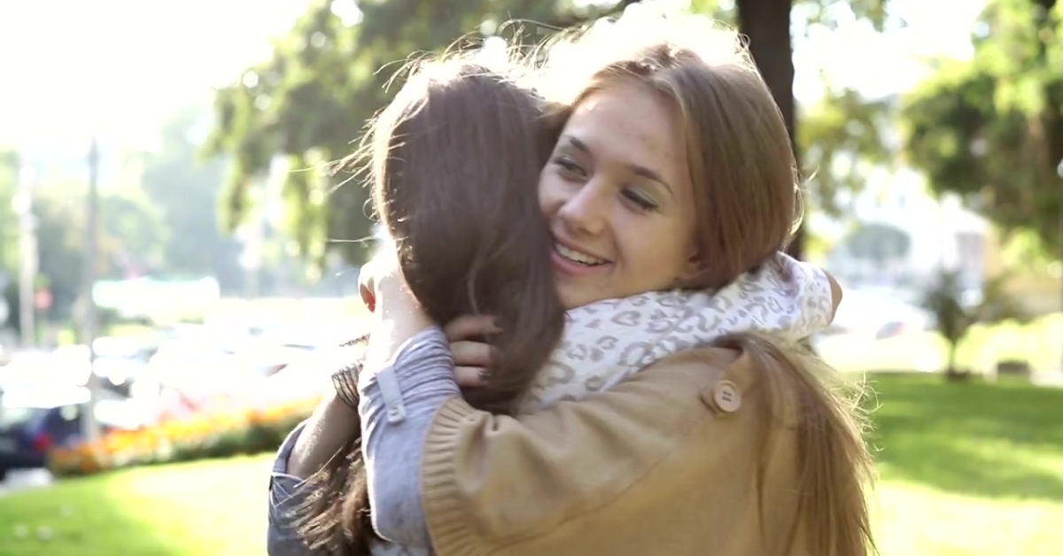 Two young women hugging outdoors, highlighting the importance of emotional support.