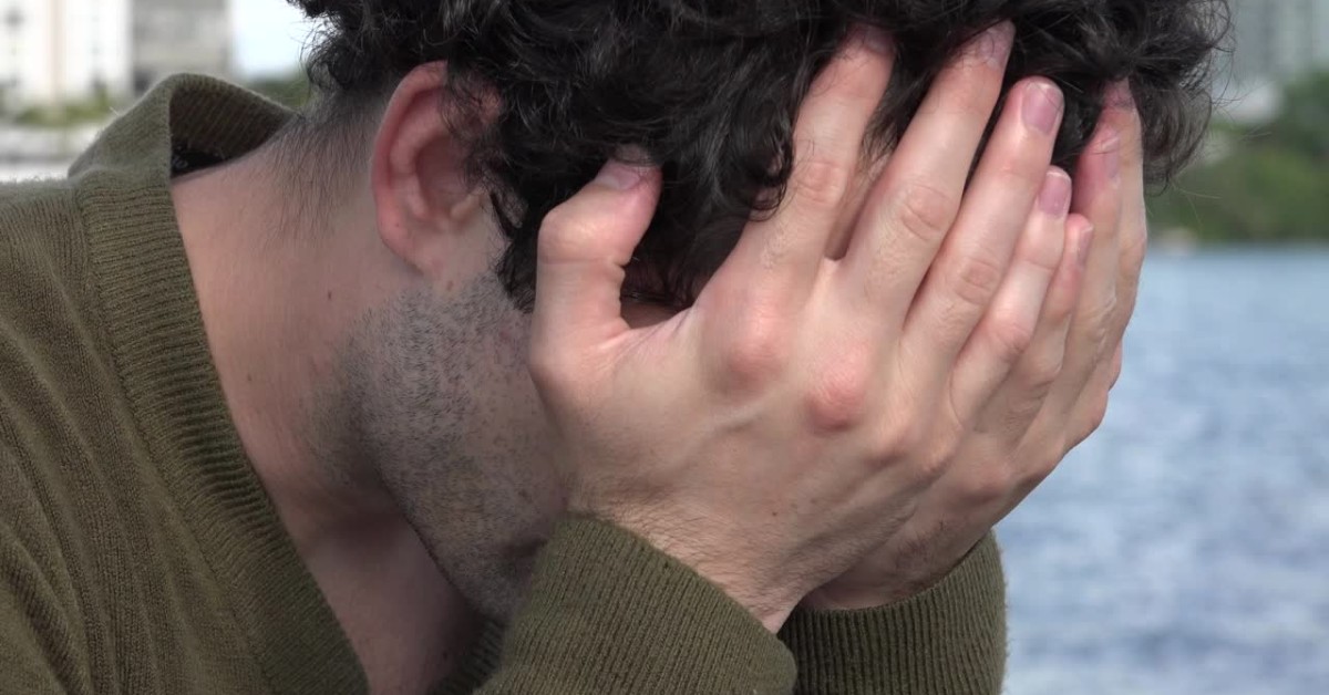 Man with head in hands, illustrating the importance of supporting employees with anxiety.