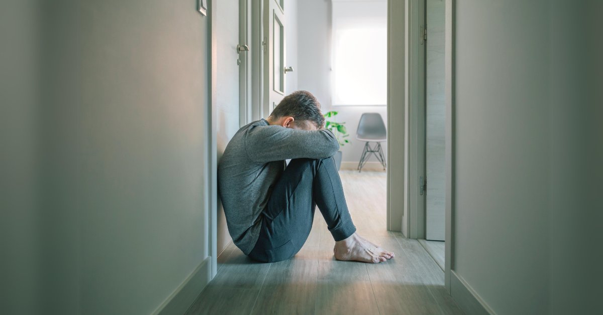 A man sits distressed in a hallway, symbolizing the importance of understanding mental health and breaking the stigma.