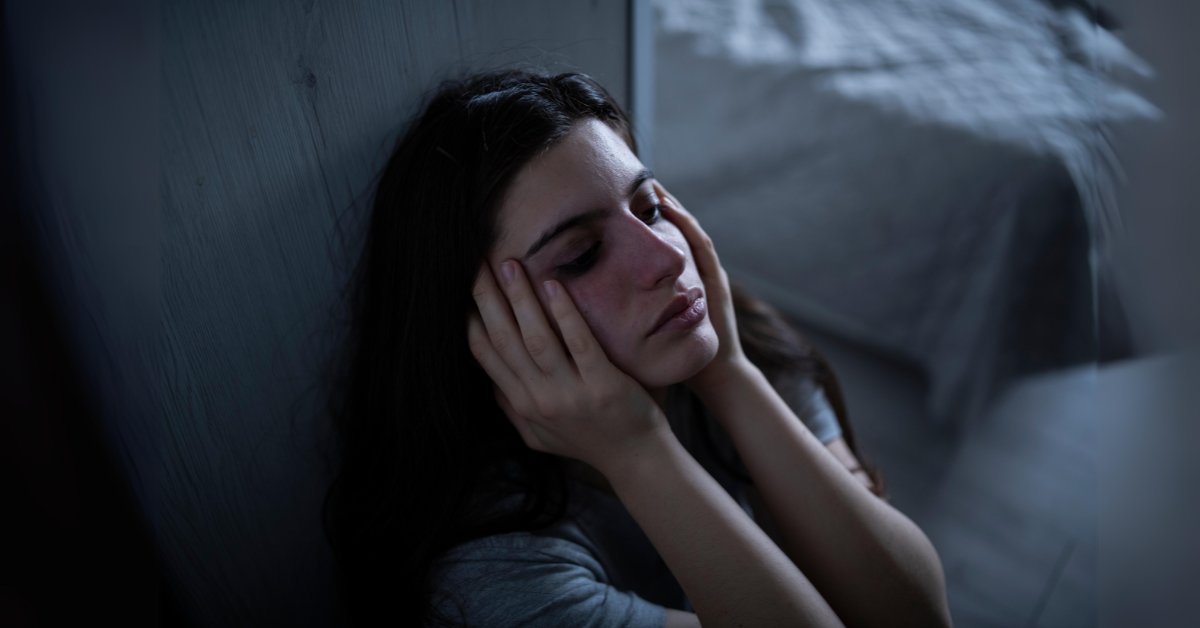 A distressed woman sits with her head in her hands, highlighting the anxiety-depression connection.