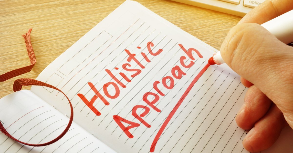 A hand writes "Holistic Approach" in a notebook, emphasizing holistic approaches to anxiety management.