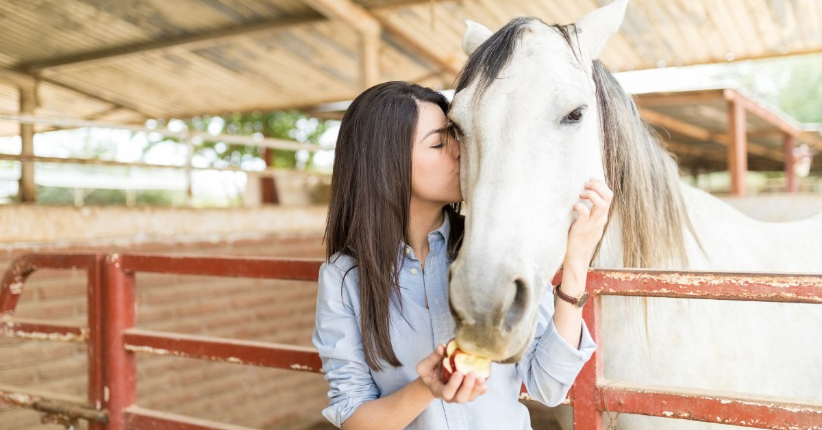 A woman kisses a horse, illustrating the benefits of equine therapy in anxiety treatment.