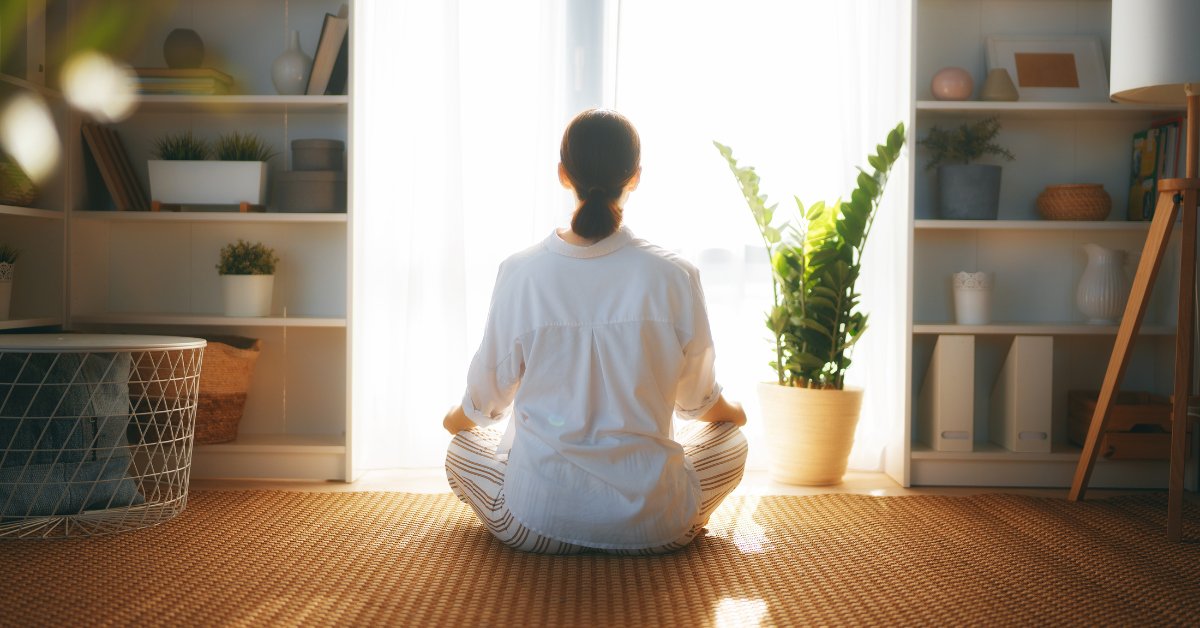 A person sits cross-legged in a peaceful room, illustrating meditation practices for anxiety reduction.