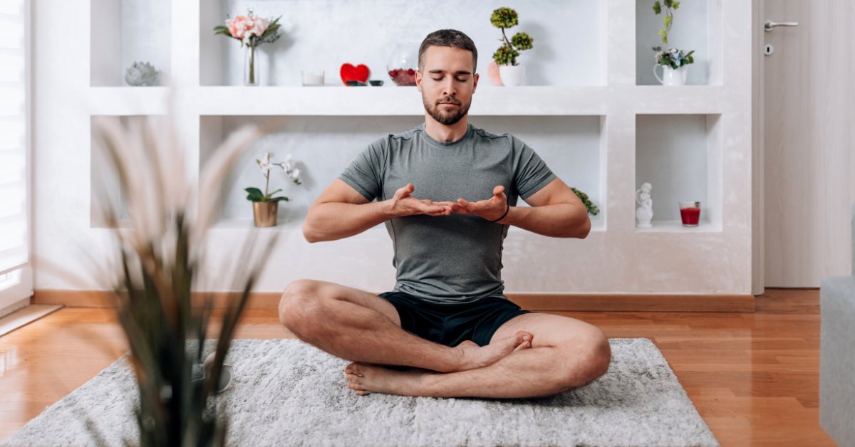 A man practices deep breathing while sitting cross-legged, demonstrating breathing exercises for anxiety control.