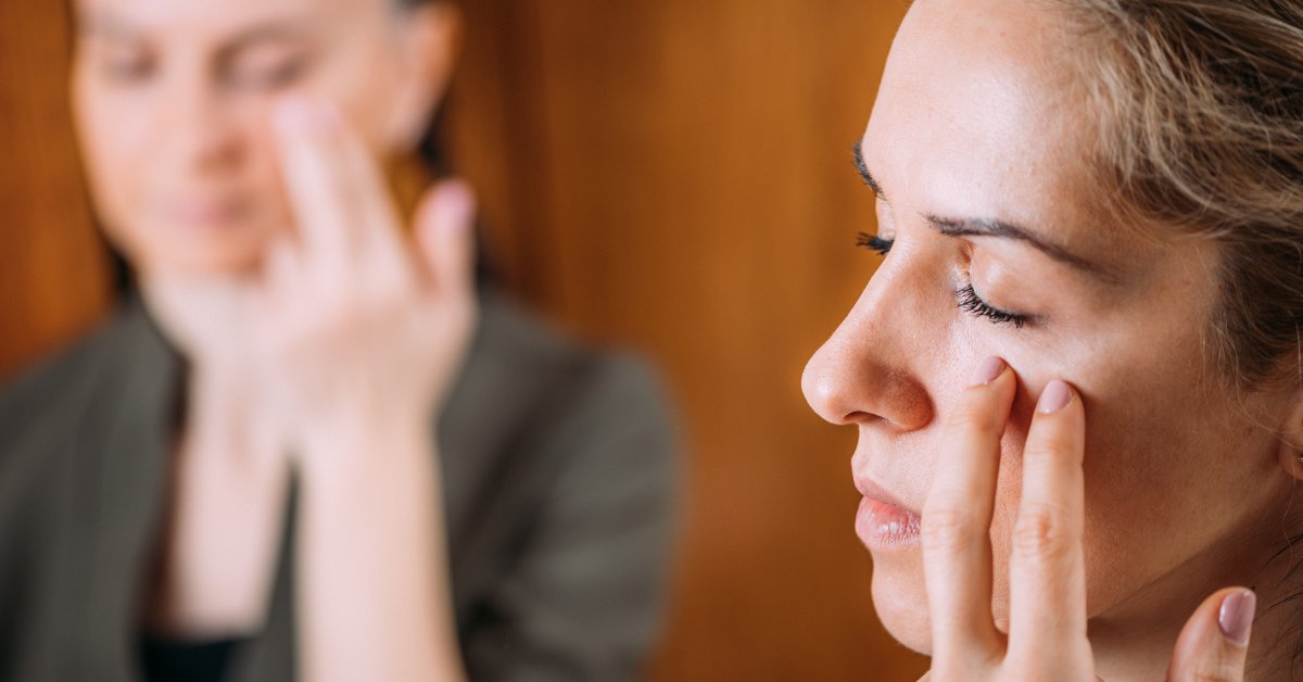 Two women practice tapping on pressure points, demonstrating relaxation techniques for anxiety relief.