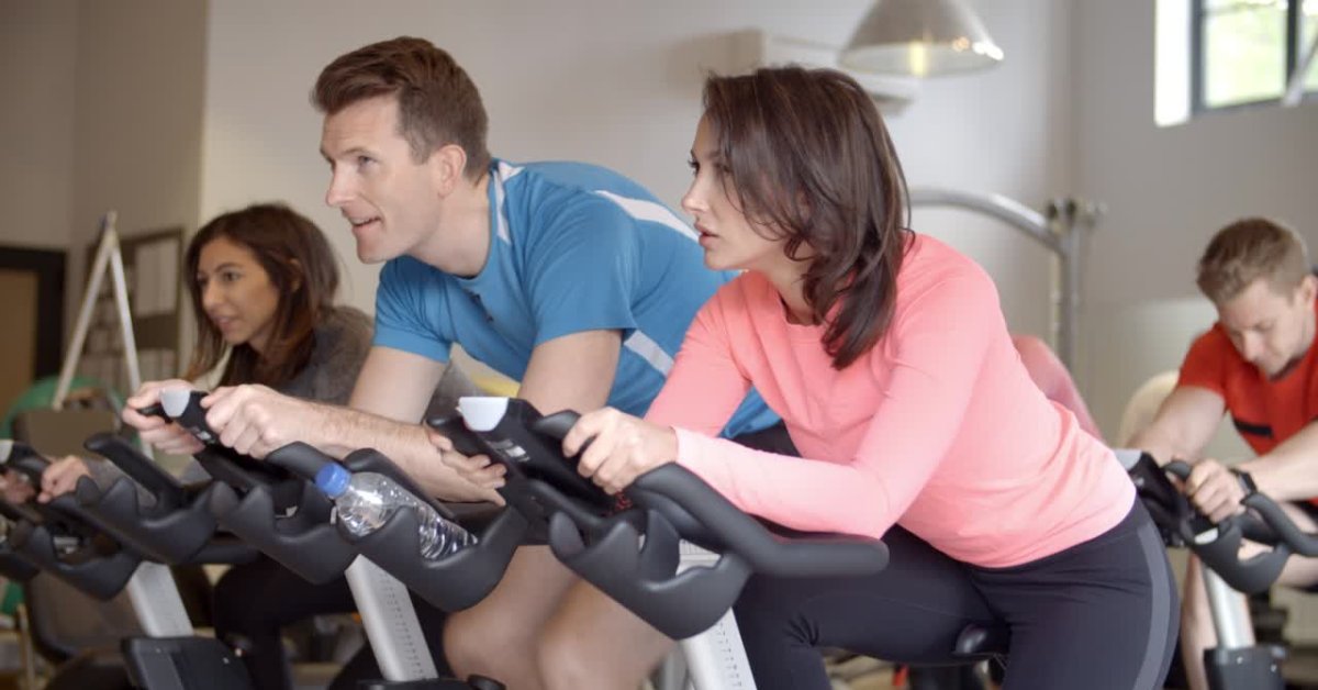 People engaged in indoor cycling, emphasizing exercise as a tool for anxiety management.